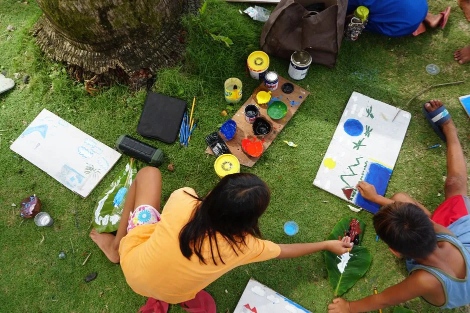 Children doing art activities together outdoors in a park