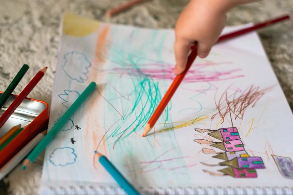 A child's hands coloring a drawing with colored pencils